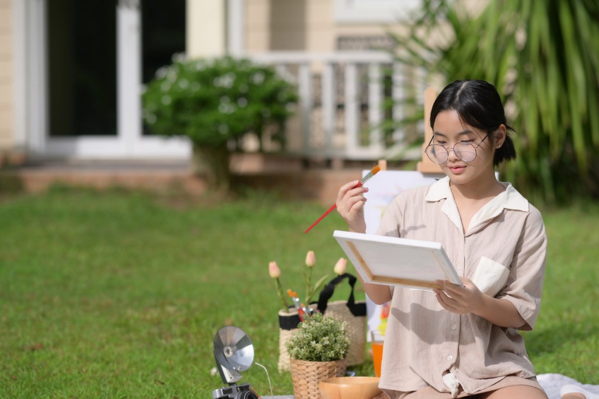 Girl painting picture in garden. Activity hobby concept.